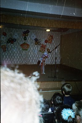 Marionette puppet performance on stage with decorative paper cutouts and vintage posters. Audience blurred, focusing on smoke...