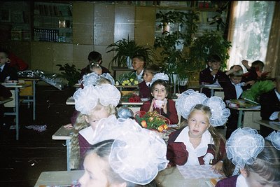 School cafeteria scene from the 1970s–1980s, featuring children in Soviet-style school uniforms with white starched collars a...
