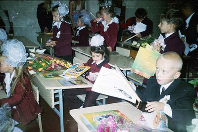 Classroom scene featuring children in early Soviet-era school uniforms (1960s–1970s), creating handmade greeting cards. Unifo...