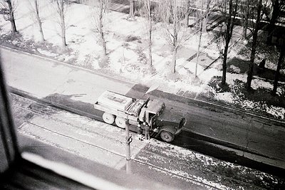 Vintage black-and-white shot of a military truck with mounted heavy machinery clearing snow from a railway track, likely mid-...