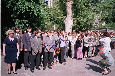 Group of students and adults in formal attire holding flowers, likely a graduation ceremony. Uniforms suggest 1970s–1980s Eas...