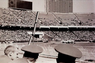 Vintage black-and-white stadium shot featuring Soviet-era signage ("ВНИМАНИЕ! ПАМЯТИ СОВЕТСКОГО СПОРТА") and tiered seating. ...