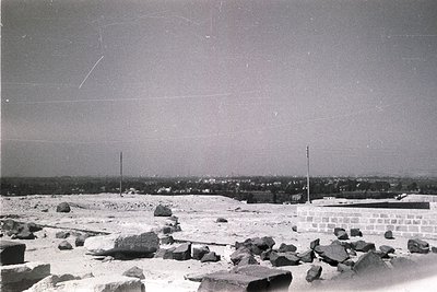 Vintage black-and-white shot of an urban construction site with scattered rubble and exposed rocks. Foreground features concr...
