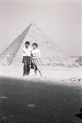 Couple posing in front of the Great Pyramid of Giza, mid-20th century. Man in short-sleeved button-up, woman in knee-length s...