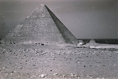 Black-and-white photograph of the Great Pyramid of Giza, showcasing its monumental scale and precise stonework. The pyramid d...