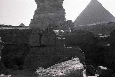 Black-and-white shot of the **Great Sphinx of Giza** with the **Pyramids of Giza** in background. Weathered limestone texture...