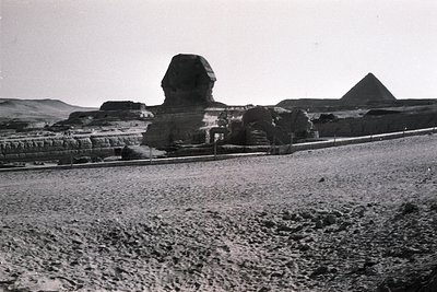 Black-and-white shot of the **Great Sphinx of Giza** with **Pyramids of Giza** in background, likely mid-20th century. Desert...