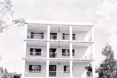 Mid-century modern seaside apartment building with three floors and balconies, featuring clean lines and minimalist design. E...