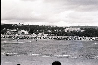 Black-and-white shot of a large-scale outdoor sports event, likely a 1950s–1960s stadium gathering. Crowds fill tiered stands...