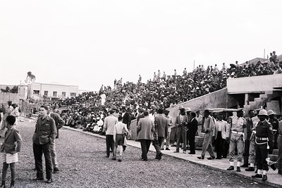Black-and-white photo of a large public gathering, likely a political rally or demonstration, featuring a dense crowd on elev...