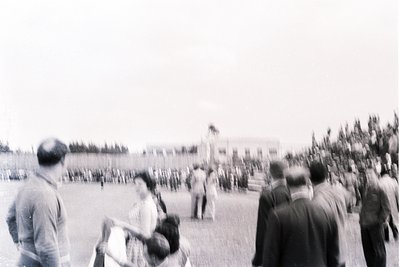 Black-and-white photo of a public gathering with military presence, likely mid-20th century. Crowd faces a row of uniformed s...