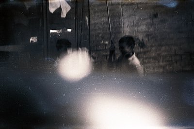 Vintage monochrome reflection of two figures in a dimly lit interior, likely a train or subway car. Blurred details suggest m...