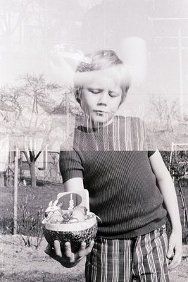 Vintage black-and-white photo of a child holding a woven basket filled with small, round objects (likely fruit or decorative ...