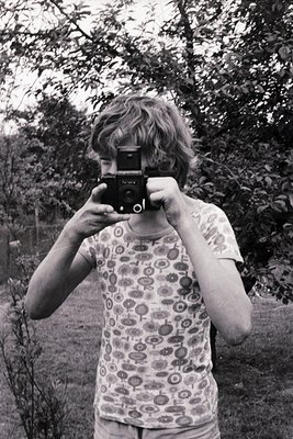 Vintage black-and-white photo of a person holding a classic **Leica M3** camera,...