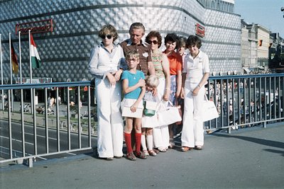 Group of seven posing on a modernist concrete bridge with geometric railings, 1970s. Six adults in coordinated white uniforms...