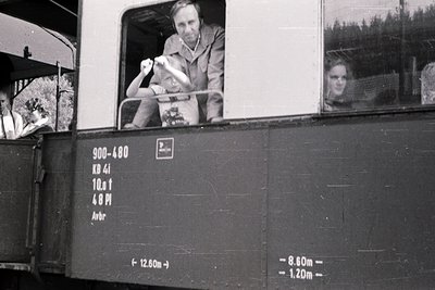 Black-and-white photo of a man waving from an open window of a vintage train car, labeled "900-480 KD 4i" with specs (10.8t, ...