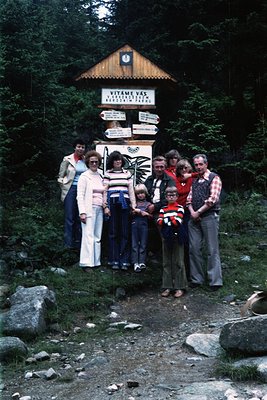 Family group photo at **Vitame Vás** (Vitame Pass) signpost in alpine forest, likely **1970s**. Wooden shelter with direction...