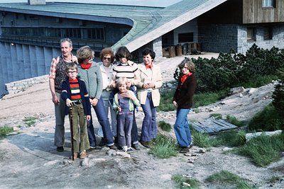 Group photo in front of a Brutalist-style building, likely a resort or public facility, with concrete overhangs and stone acc...