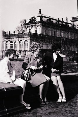 Three women in 1960s European fashion pose near the **Sofia Palace (Dvorets na Vitosha)** in Bulgaria. Centered on a stone be...