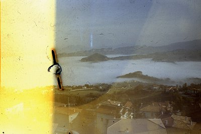 Vintage sepia-toned aerial view of coastal settlement with waterfront and inland hills. Likely Mediterranean or Adriatic regi...