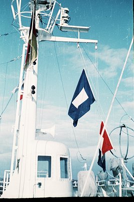 Maritime signal flag display on a vessel’s mast, featuring the Danish flag (red/white) and a blue flag with a white "D" (Dani...