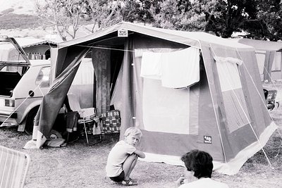 Campsite scene featuring a vintage canvas tent () with a vintage van and folding chairs. A child sits near the tent entrance,...