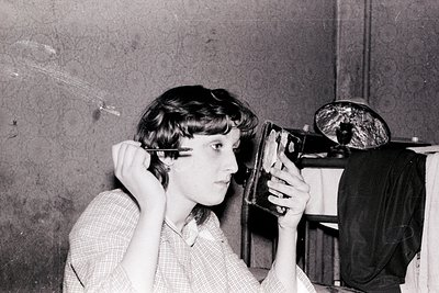 Black-and-white portrait of a person using a vintage **Leica camera** with a close-up lens, likely from the **1950s–1970s**. ...