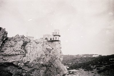 Historic stone tower perched on rugged cliff edge, likely a medieval watchtower or fortress. Architectural details include cr...