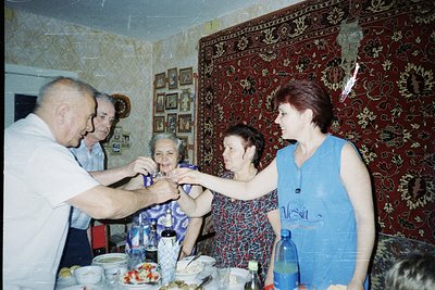 Vintage indoor gathering featuring five adults in a modestly decorated room, likely Eastern Europe, 1970s–1980s. A man in a w...