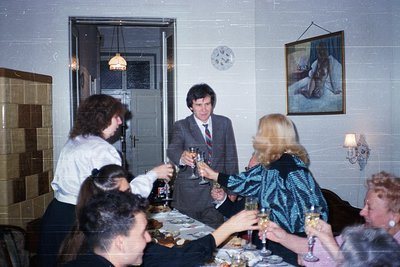 Vintage indoor gathering in a tiled room with 1970s-era decor: six adults in formal attire (men in suits, women in dresses) s...