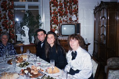 Vintage family portrait in a formal dining setting, likely 1970s–1980s. Three adults and an elderly woman seated around a tab...