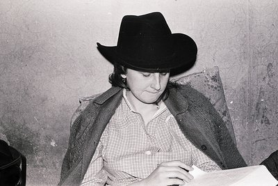 Portrait of a person in a cowboy hat and checkered shirt, seated indoors. The vintage monochrome style suggests mid-20th cent...