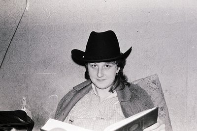Black-and-white portrait of a person wearing a wide-brimmed cowboy hat indoors, holding an open book. Mid-20th century fashio...