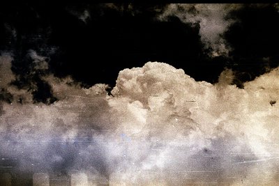 Dramatic cloudscape with a high-contrast, textured appearance. Extensive scratches and dust marks suggest age and possible fi...