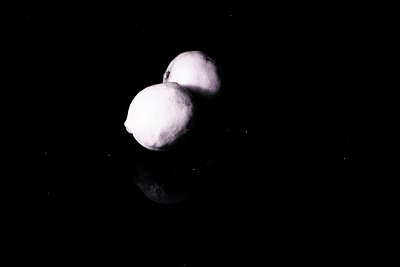 Striking black and white still life featuring two lemons suspended against a dark background, creating a minimalist compositi...