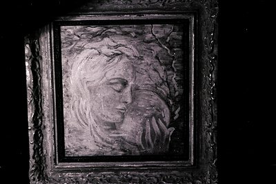 A framed portrait depicts a solemn, woman's face with closed eyes, possibly depicting sorrow or reverence. The artwork's styl...