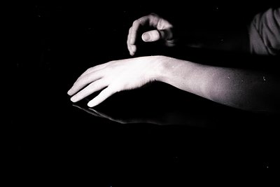 A grayscale photograph showcases a hand, seemingly poised above a reflective surface. The hand is slightly blurred, suggestin...