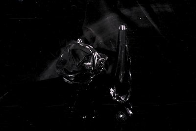 A detailed black and white still life featuring a heavily creased and distorted plastic bag. The bag's form is bulbous and ir...