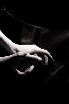 Close-up of two hands reaching toward one another against a dark, textured background. The image evokes intimacy & connection...