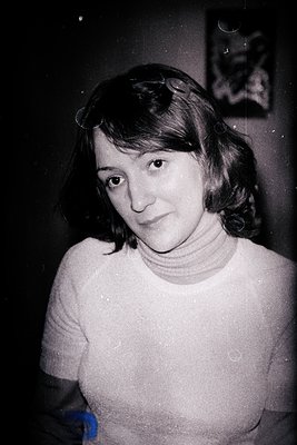 B&W portrait of a young woman with short, wavy hair and a turtleneck sweater. Direct gaze; appears slightly melancholic. Visi...