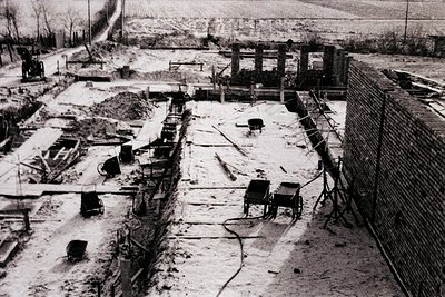 Aerial view of a mid-20th-century industrial site in ruins, featuring collapsed brick structures, exposed machinery, and scat...