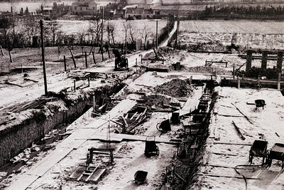 Aerial view of a heavily damaged urban area post-war, likely 1940s–1950s. Ruined buildings, exposed foundations, and scattere...