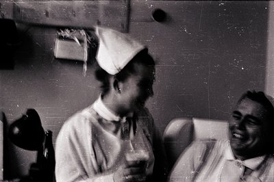 Vintage black-and-white photo of two individuals in formal attire, likely 1940s–1950s. Woman wears a graduation cap and gown;...
