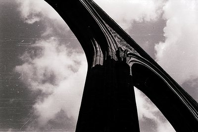 Mid-century modernist bridge support with sleek, curved concrete arches against stormy skies. Minimalist architectural detail...