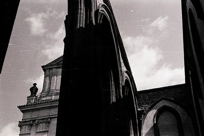 Classic black-and-white shot of Gothic Revival architecture—pointed arches, ornate stone detailing, and a weathered facade un...