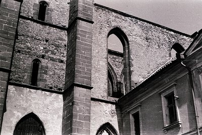 Historic stone church facade featuring pointed Gothic arches and weathered brickwork. The structure appears to be in a state ...