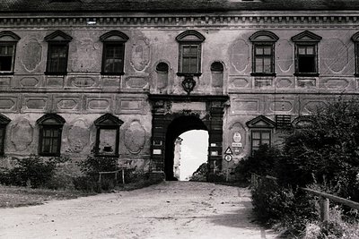 Historic grand entrance archway with Baroque-style facade, featuring decorative moldings and ornate window frames. The struct...