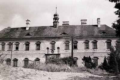Neoclassical building with symmetrical façade, arched windows, and decorative cornices. Central dome and smaller chimneys sug...