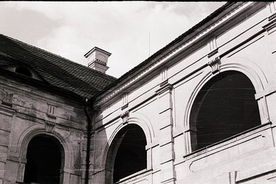Neoclassical façade featuring three arched openings with decorative keystones and cornice detailing. Black-and-white photo su...