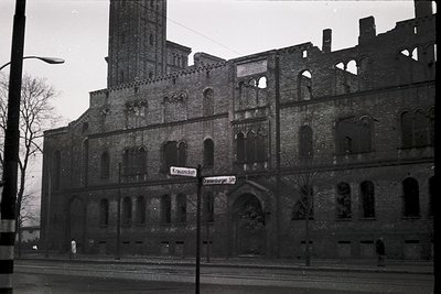 Historic brick building with Gothic Revival elements—tall arched windows, decorative stonework, and a central tower. Street s...